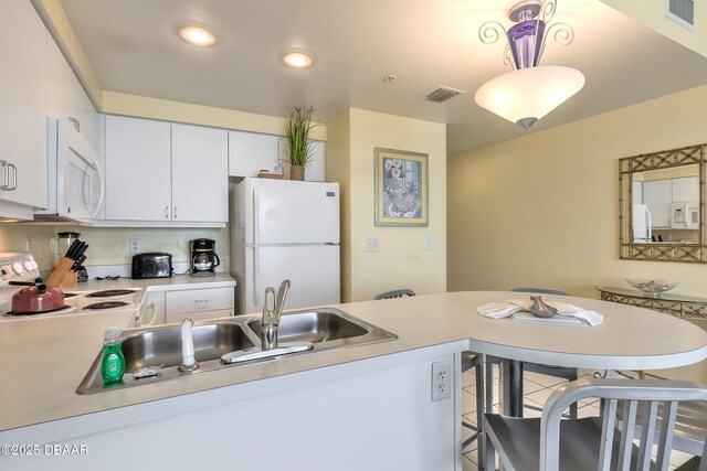 kitchen featuring visible vents, white appliances, light countertops, and a sink