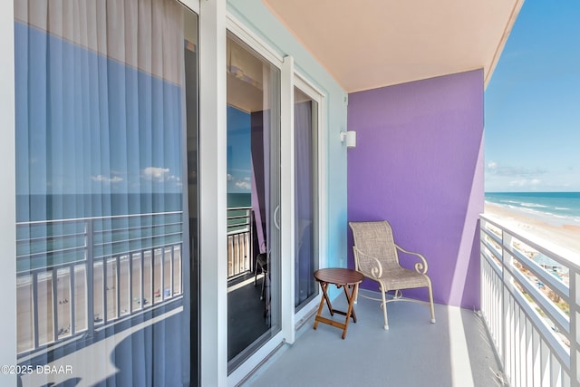 balcony with a water view and a view of the beach