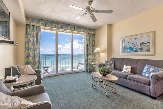 living room with carpet flooring, a textured ceiling, ceiling fan, and a water view