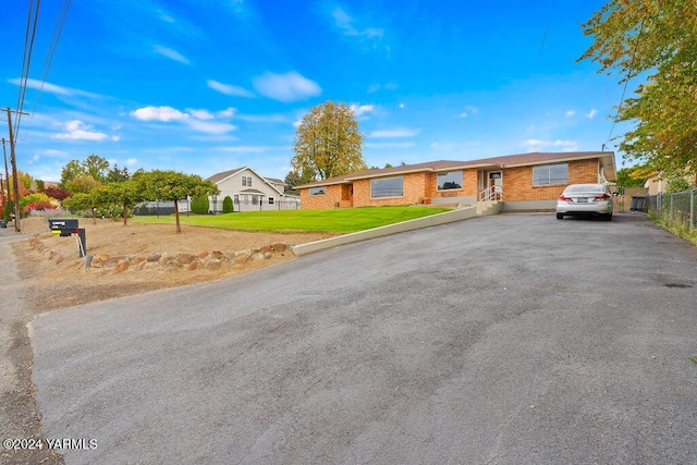 ranch-style home featuring a residential view, fence, and a front yard