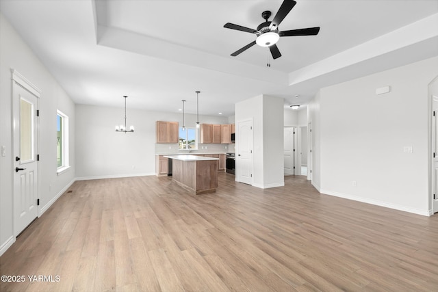 4608 W Larch Ave, Yakima, WA 98908 - unfurnished living room with light wood finished floors, ceiling fan, a raised ceiling, and healthy amount of natural light
