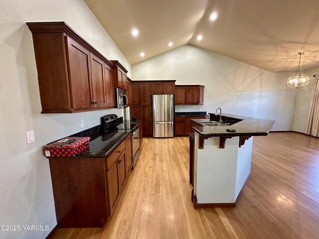 1010 S 89th Ave, Yakima, WA 98908 - kitchen with stainless steel appliances, a sink, dark countertops, a breakfast bar area, and light wood finished floors