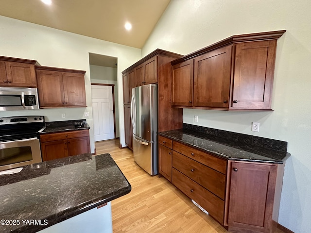 1010 S 89th Ave, Yakima, WA 98908 - kitchen with stainless steel appliances, light wood-style floors, dark stone counters, vaulted ceiling, and recessed lighting