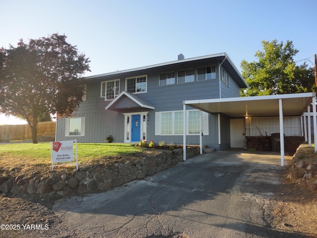 view of front of home featuring driveway, a front lawn, fence, and an attached carport