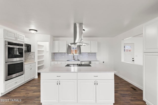 12307 Tieton Dr, Yakima, WA 98908 - kitchen featuring black appliances, island exhaust hood, a sink, decorative backsplash, and light countertops