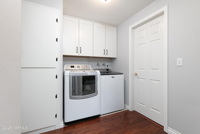 clothes washing area with cabinet space, washing machine and dryer, baseboards, and dark wood finished floors