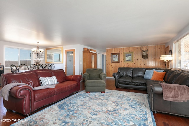 living room featuring an inviting chandelier, wooden walls, and wood finished floors