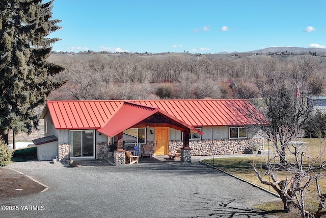 chalet / cabin with a standing seam roof, stone siding, metal roof, and covered porch