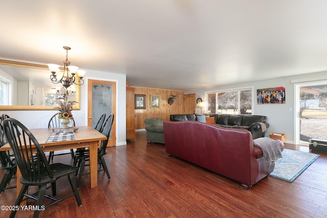 living room with an inviting chandelier, baseboards, wood finished floors, and wood walls