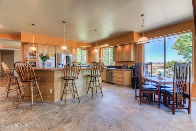 11901 Zier Rd, Yakima, WA 98908 - kitchen with appliances with stainless steel finishes, a kitchen bar, light stone finish floors, hanging light fixtures, and light brown cabinets