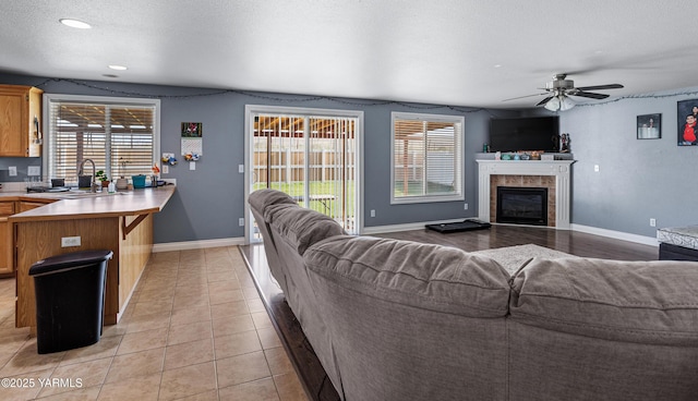 506 Millenium Ave, Moxee, WA 98936 - living room featuring healthy amount of natural light, a ceiling fan, a tiled fireplace, a textured ceiling, and light tile patterned floors