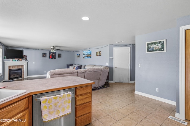 506 Millenium Ave, Moxee, WA 98936 - kitchen with stainless steel dishwasher, open floor plan, light countertops, light tile patterned floors, and a tile fireplace