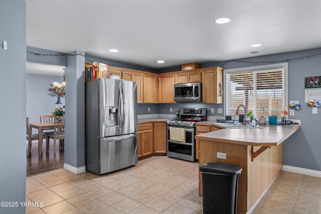 506 Millenium Ave, Moxee, WA 98936 - kitchen featuring appliances with stainless steel finishes, a peninsula, light countertops, light tile patterned flooring, and a kitchen bar