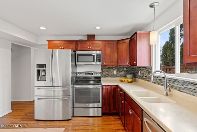 kitchen featuring light wood finished floors, light countertops, a sink, and stainless steel appliances