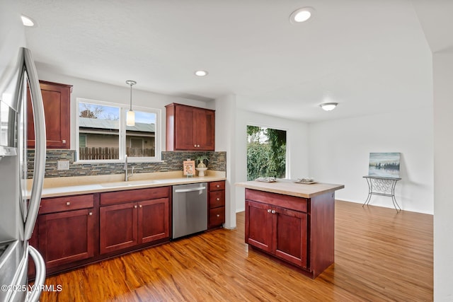 kitchen featuring a sink, tasteful backsplash, appliances with stainless steel finishes, light wood-type flooring, and dark brown cabinets