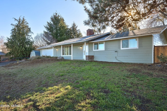 single story home with a garage, a front yard, fence, and a chimney