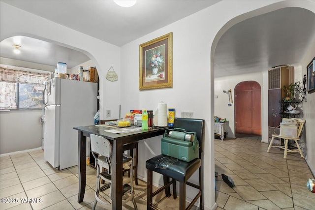 kitchen featuring light tile patterned floors, arched walkways, and freestanding refrigerator