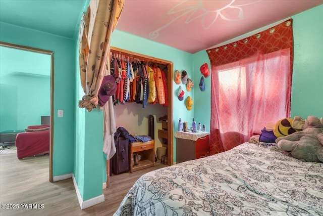 bedroom with a closet, baseboards, and wood finished floors