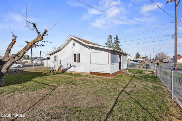 rear view of house featuring fence and a lawn