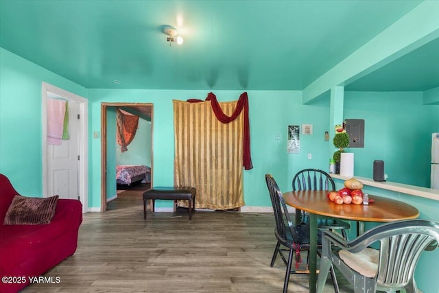 dining area featuring wood finished floors, electric panel, and baseboards