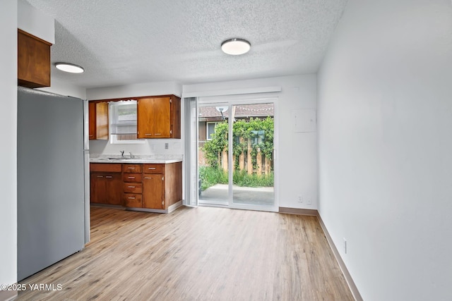 904 S 42nd Ave Unit A, B, C, D, Yakima, WA 98908 - kitchen featuring light countertops, brown cabinetry, light wood-style flooring, freestanding refrigerator, and a textured ceiling