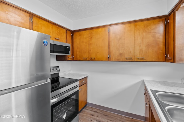 904 S 42nd Ave Unit A, B, C, D, Yakima, WA 98908 - kitchen with stainless steel appliances, brown cabinets, wood finished floors, a textured ceiling, and light countertops
