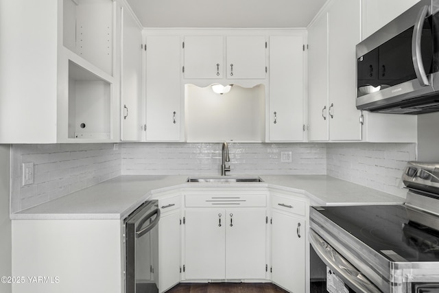 kitchen with light countertops, appliances with stainless steel finishes, a sink, and white cabinets