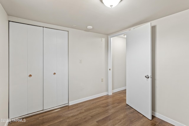 unfurnished bedroom with a closet, baseboards, and wood finished floors