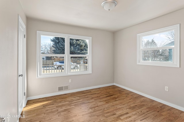 unfurnished room featuring visible vents, baseboards, and wood finished floors