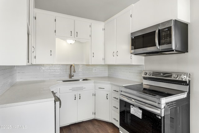 kitchen featuring a sink, white cabinetry, appliances with stainless steel finishes, backsplash, and dark wood finished floors