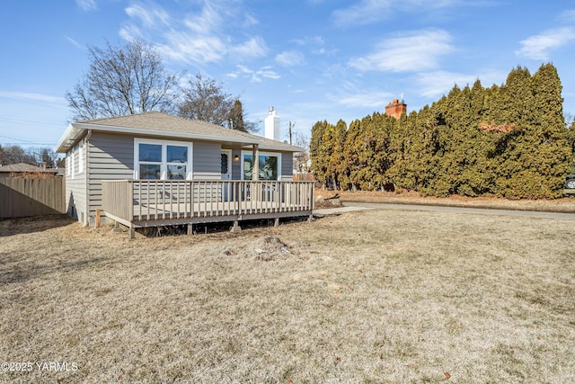 ranch-style home featuring a shingled roof, fence, and a wooden deck