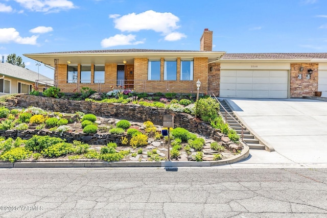 single story home featuring a chimney, stairs, brick siding, an attached garage, and driveway