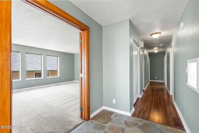 corridor with baseboards and wood finished floors