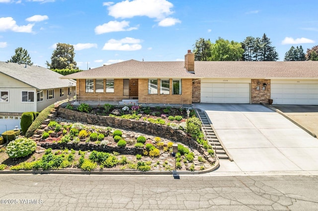 ranch-style home with roof with shingles, an attached garage, brick siding, a chimney, and driveway
