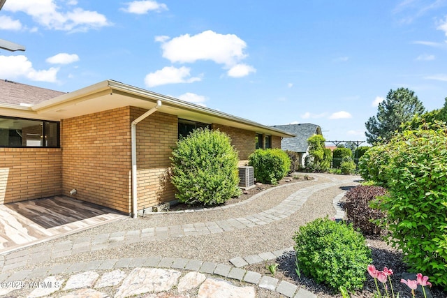 view of side of property with central AC unit and brick siding