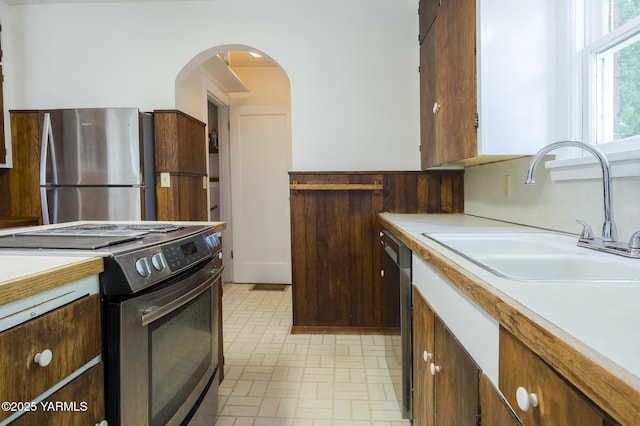 418 S 32nd Ave, Yakima, WA 98902 - kitchen featuring appliances with stainless steel finishes, a sink, light countertops, brick patterned floors, and arched walkways