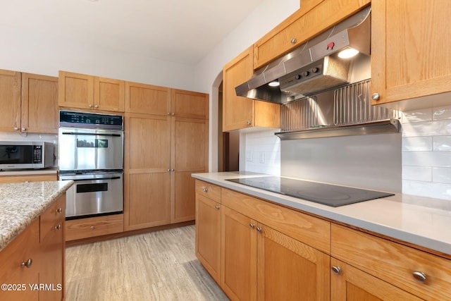 1011 N 79th Ave, Yakima, WA 98908 - kitchen with appliances with stainless steel finishes, under cabinet range hood, decorative backsplash, and light wood finished floors