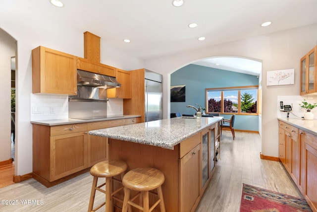 1011 N 79th Ave, Yakima, WA 98908 - kitchen featuring arched walkways, built in fridge, under cabinet range hood, vaulted ceiling, and tasteful backsplash