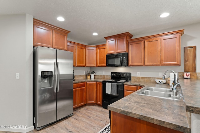 212 Golding St, Moxee, WA 98936 - kitchen featuring black appliances, brown cabinetry, light wood-type flooring, recessed lighting, and a peninsula