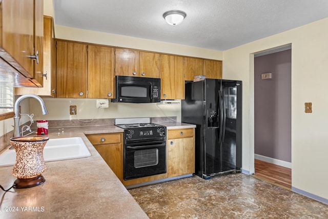 kitchen featuring brown cabinets, light countertops, a textured ceiling, black appliances, and a sink