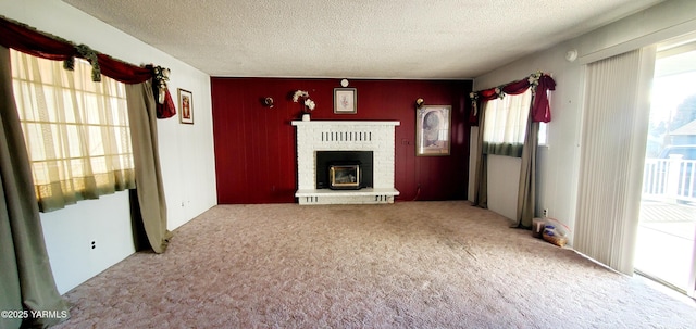 unfurnished living room featuring a textured ceiling, a brick fireplace, and carpet flooring