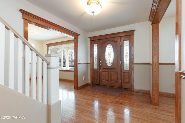 foyer entrance with stairs, baseboards, and light wood-type flooring
