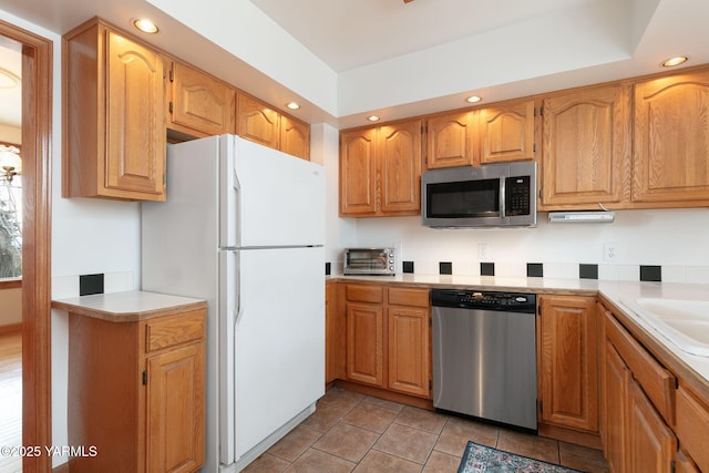 kitchen with appliances with stainless steel finishes, light countertops, recessed lighting, light tile patterned floors, and brown cabinetry