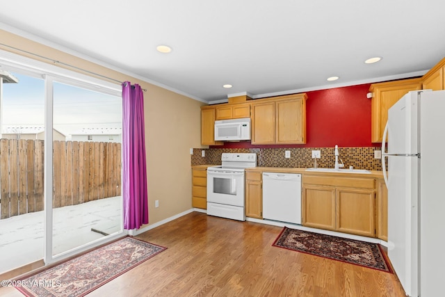 kitchen with white appliances, wood finished floors, a sink, light countertops, and tasteful backsplash