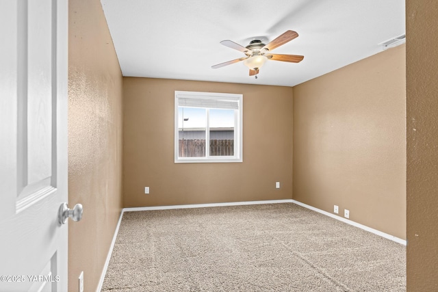 carpeted spare room featuring visible vents, baseboards, and ceiling fan