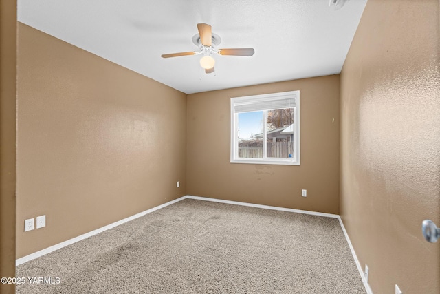 carpeted empty room with a ceiling fan, baseboards, and a textured wall