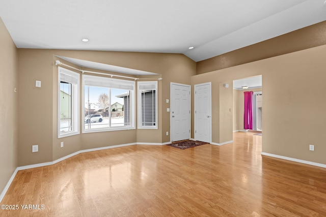 interior space featuring vaulted ceiling, light wood-style floors, and baseboards