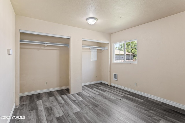 921 N 29th Ave, Yakima, WA 98902 - unfurnished bedroom featuring two closets, wood finished floors, a textured ceiling, and heating unit