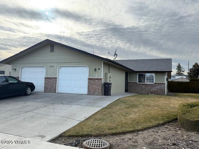 single story home with concrete driveway, an attached garage, brick siding, and a front lawn