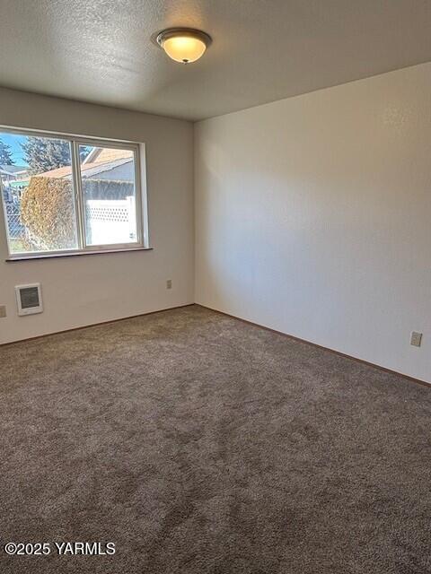 carpeted empty room with a textured ceiling